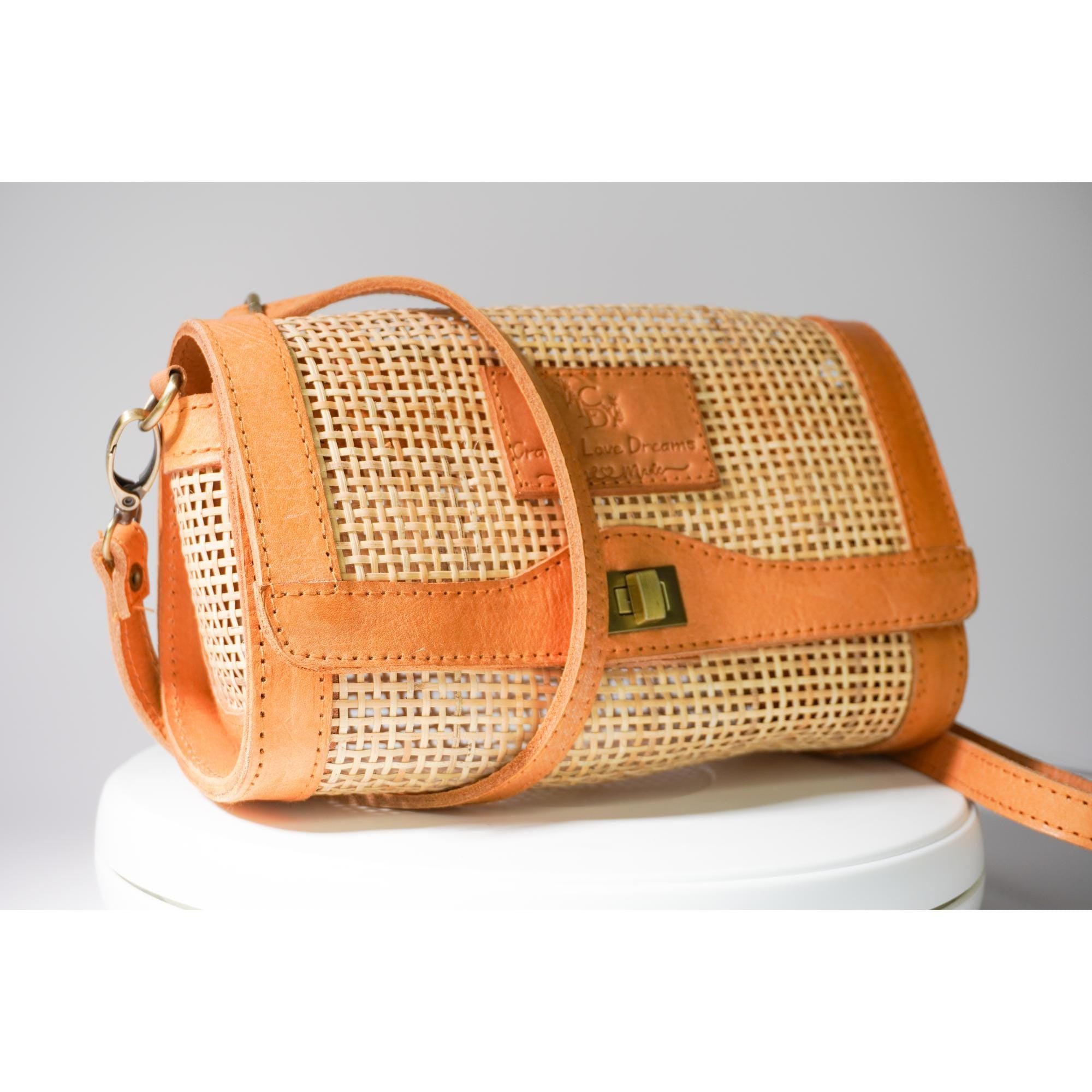 A handbag with a woven texture and a leather strap, sitting on a white surface.