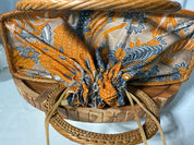 a woven basket with a patterned fabric covering the interior. The basket has a wooden handle and is placed on a wooden surface.