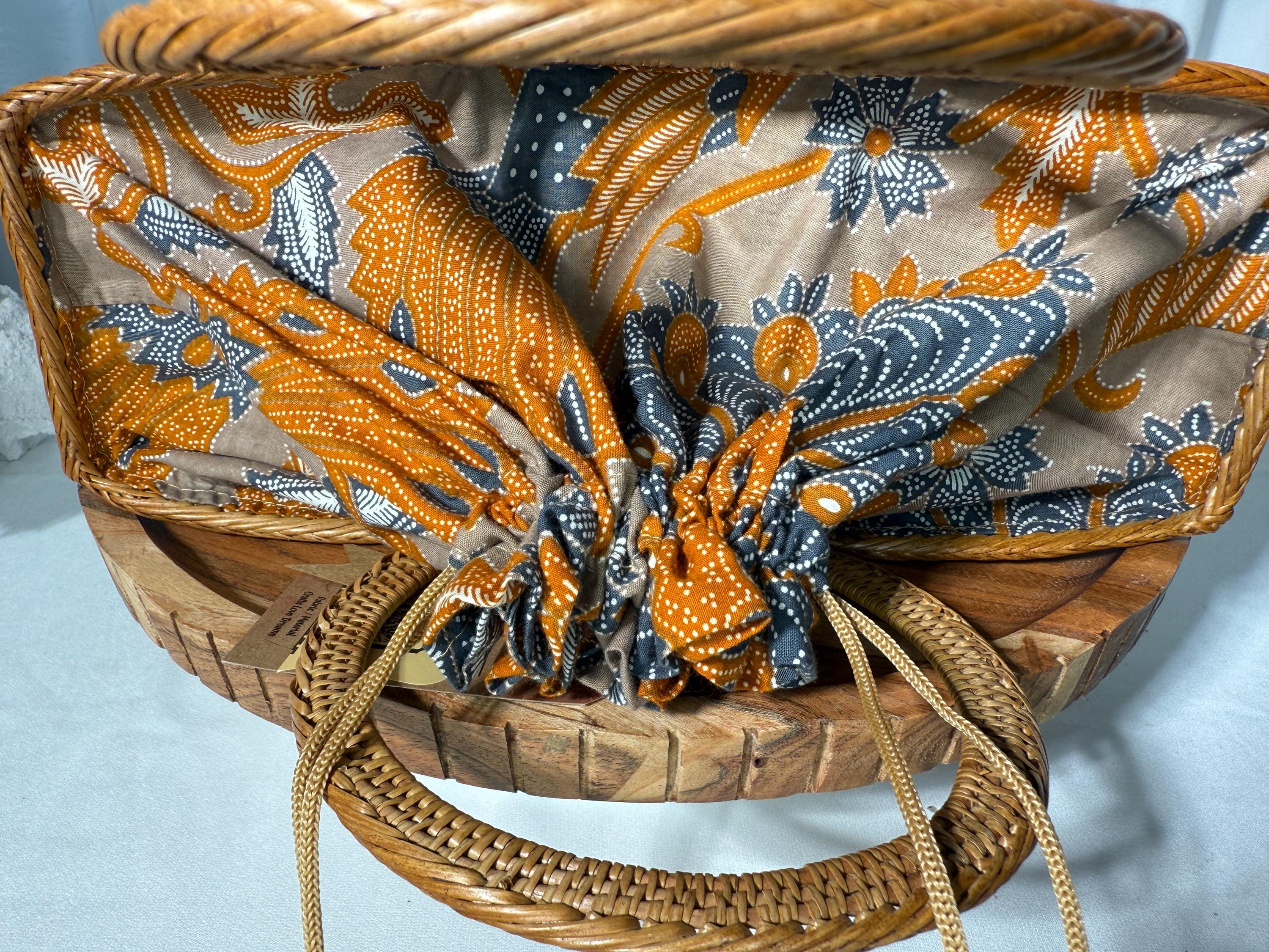 a woven basket with a patterned fabric covering the interior. The basket has a wooden handle and is placed on a wooden surface.