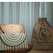 two handcrafted bags, one striped and one burlap, placed next to a burlap bag with a logo, all sitting on a wooden surface.