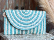 A handbag with a striped pattern in shades of blue and white, placed on a decorative surface.