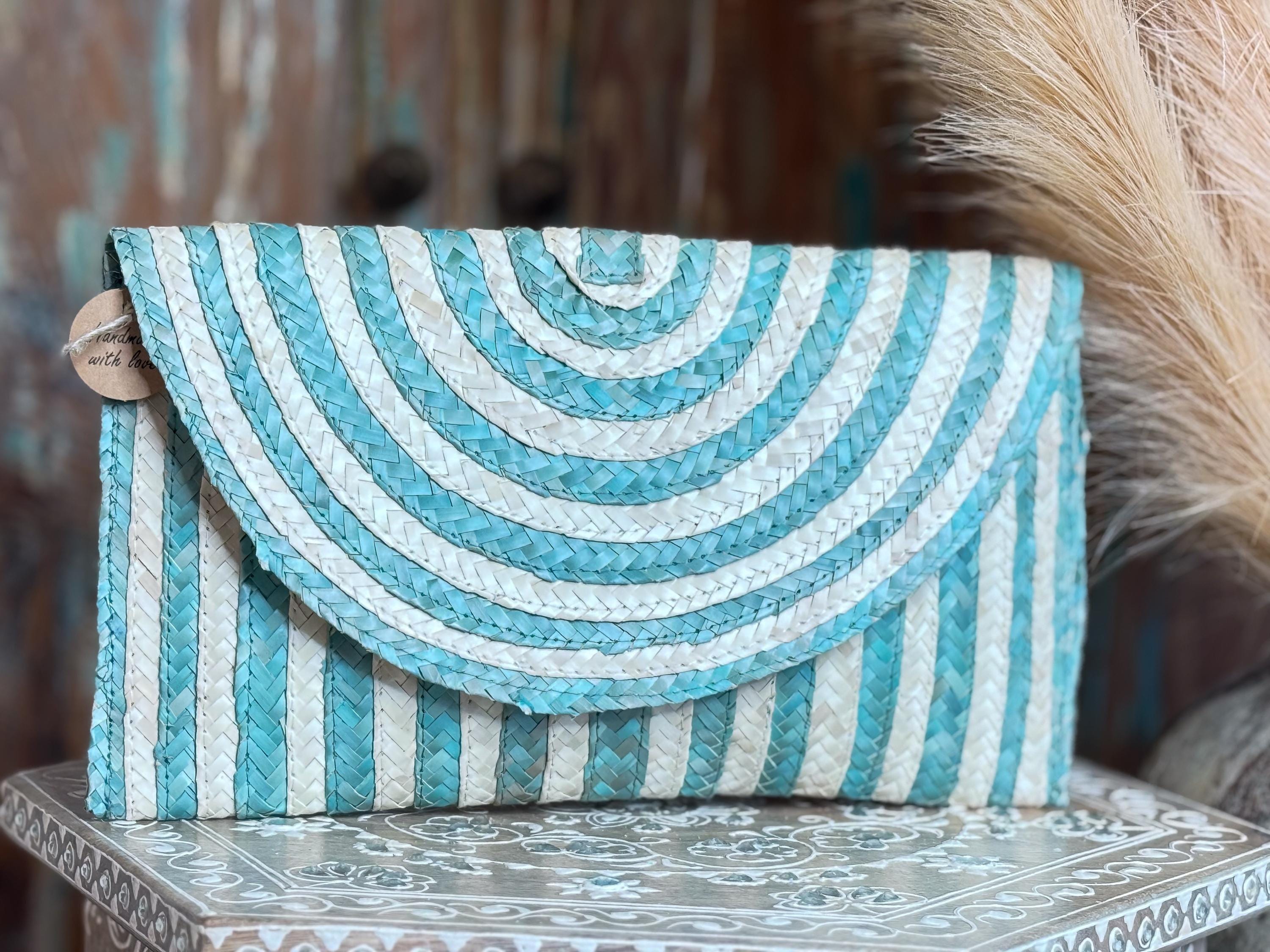 A handbag with a striped pattern in shades of blue and white, placed on a decorative surface.