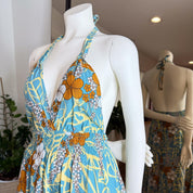 A mannequin wearing a blue and orange floral print dress with a halter neckline and a ruched waist.