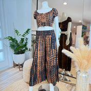 A mannequin wearing a black and orange tie-dye dress and skirt, displayed in a clothing store.