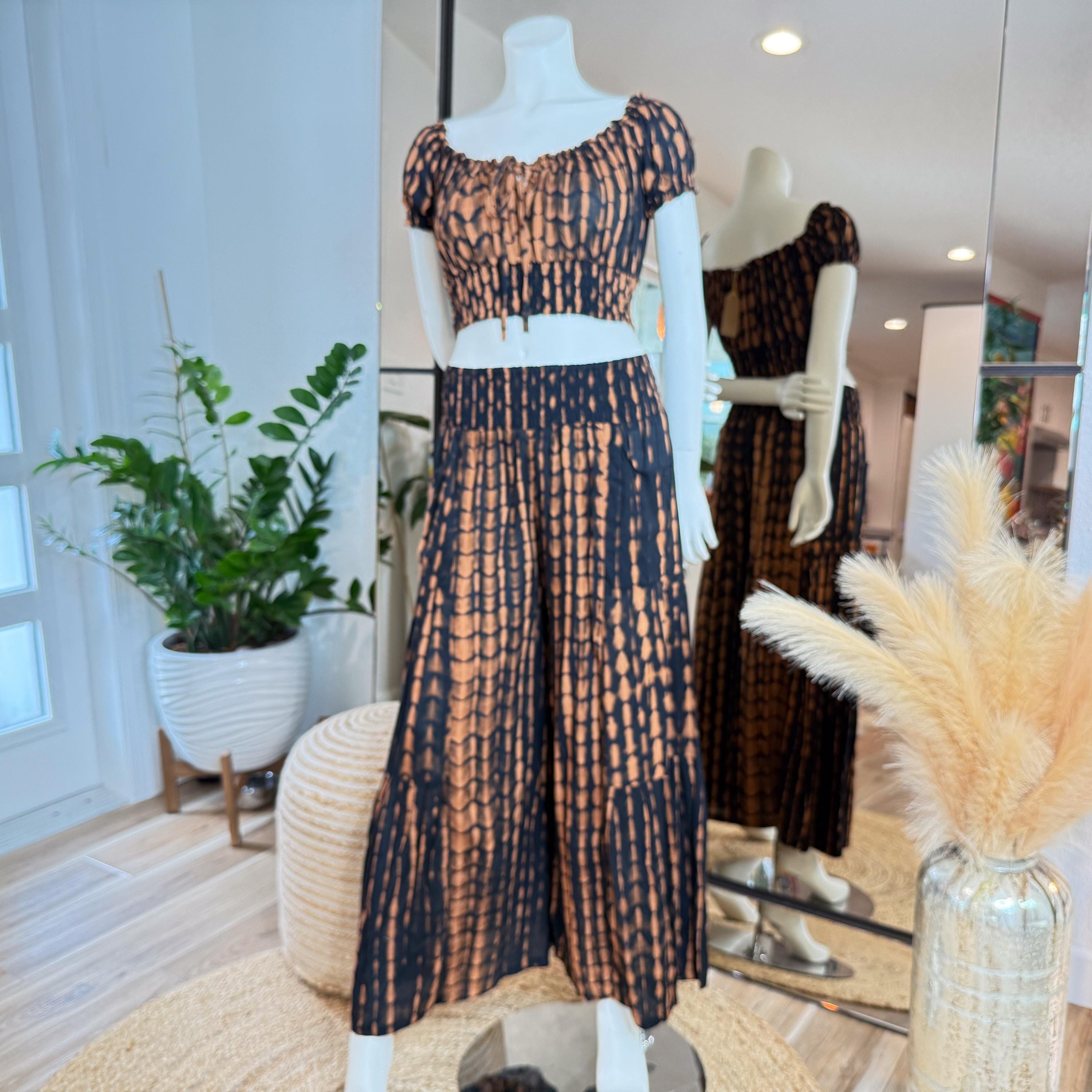 A mannequin wearing a black and orange tie-dye dress and skirt, displayed in a clothing store.