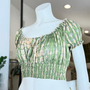 A mannequin wearing a green and white tie-dye crop top with a ruffled collar and a high-waisted design.