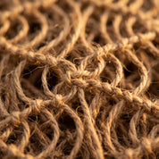 A close-up view of a tightly woven, tangled web of brown rope or cord, with the individual strands overlapping and intertwining in a complex pattern.