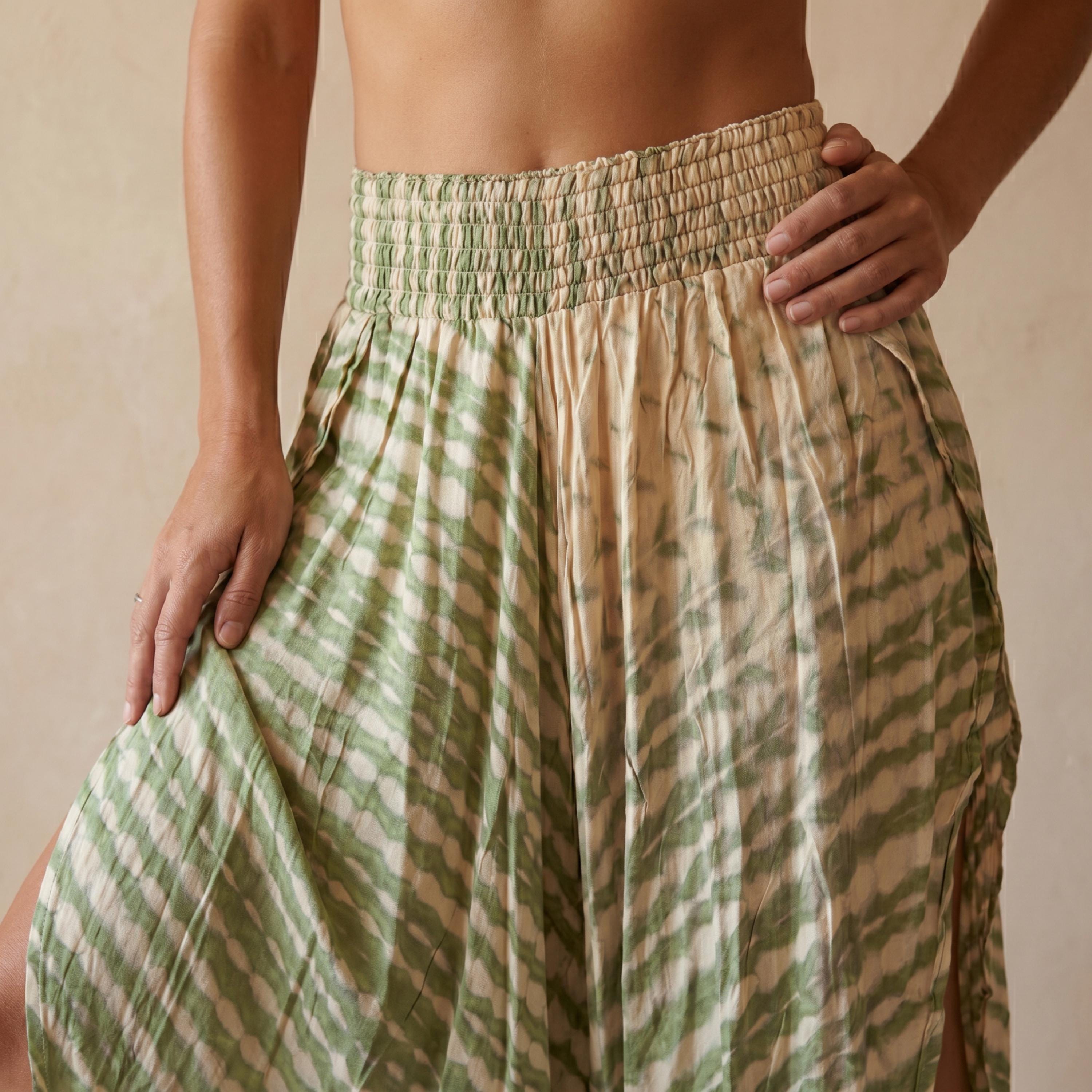 A woman wearing a green and white patterned skirt with her hand on her hip.