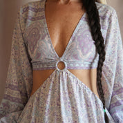 A woman wearing a long-sleeved dress with a floral pattern and a cutout in the front.