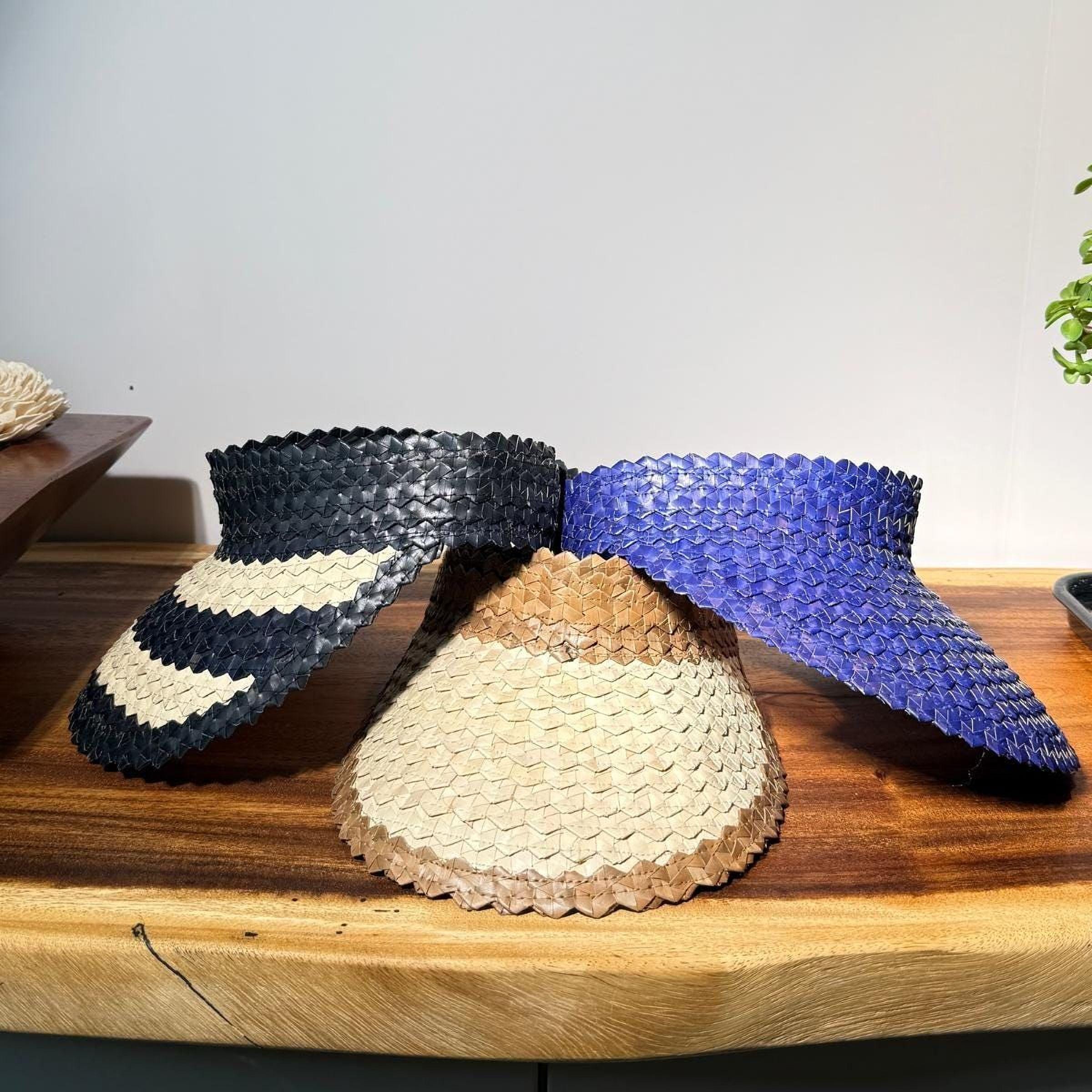 Three woven sun visors in different colors - black, white, and blue - are displayed on a wooden surface.