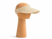 A wooden mannequin head wearing a beige sun visor.