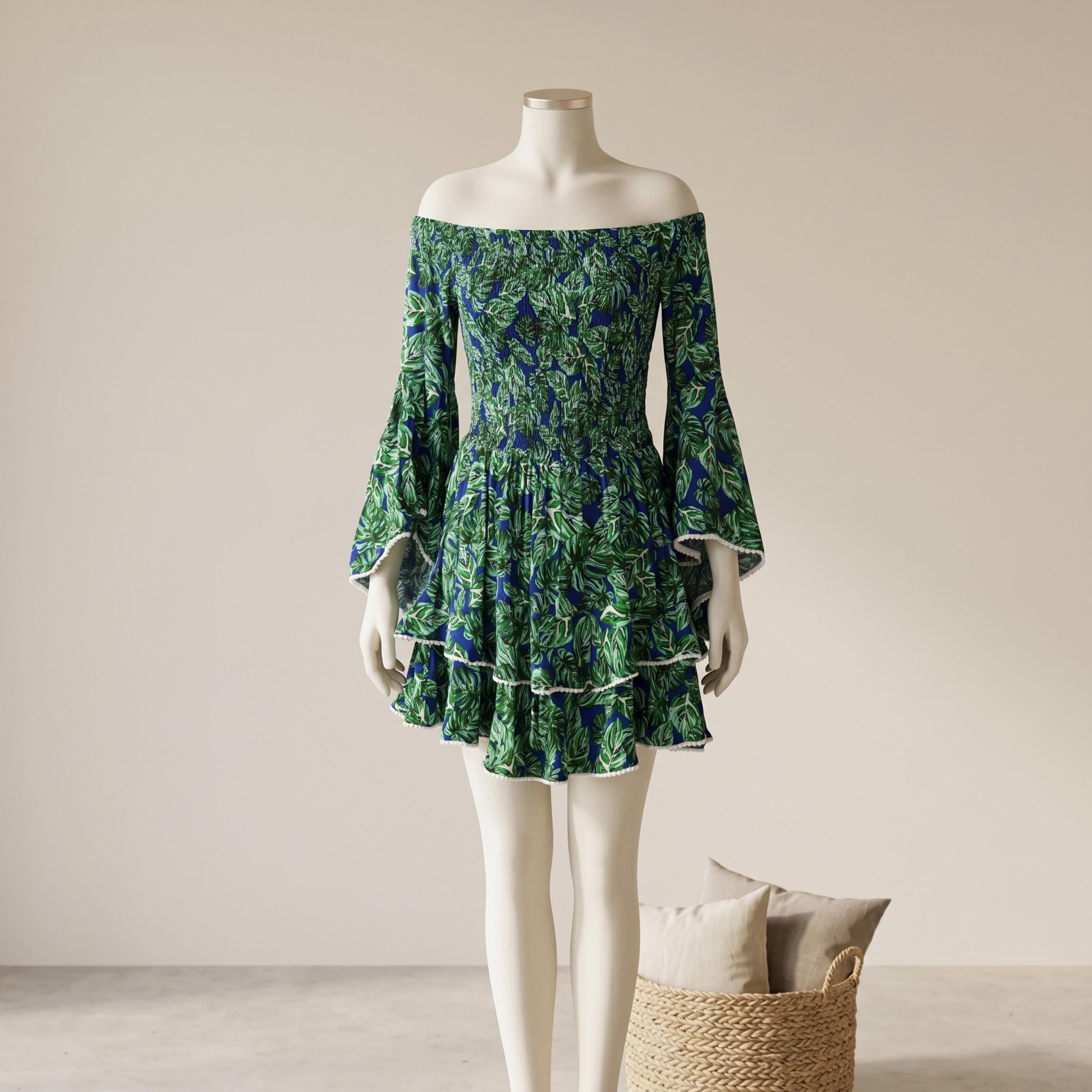A mannequin wearing a green and blue floral print dress with bell sleeves and a short skirt, standing next to a woven basket.