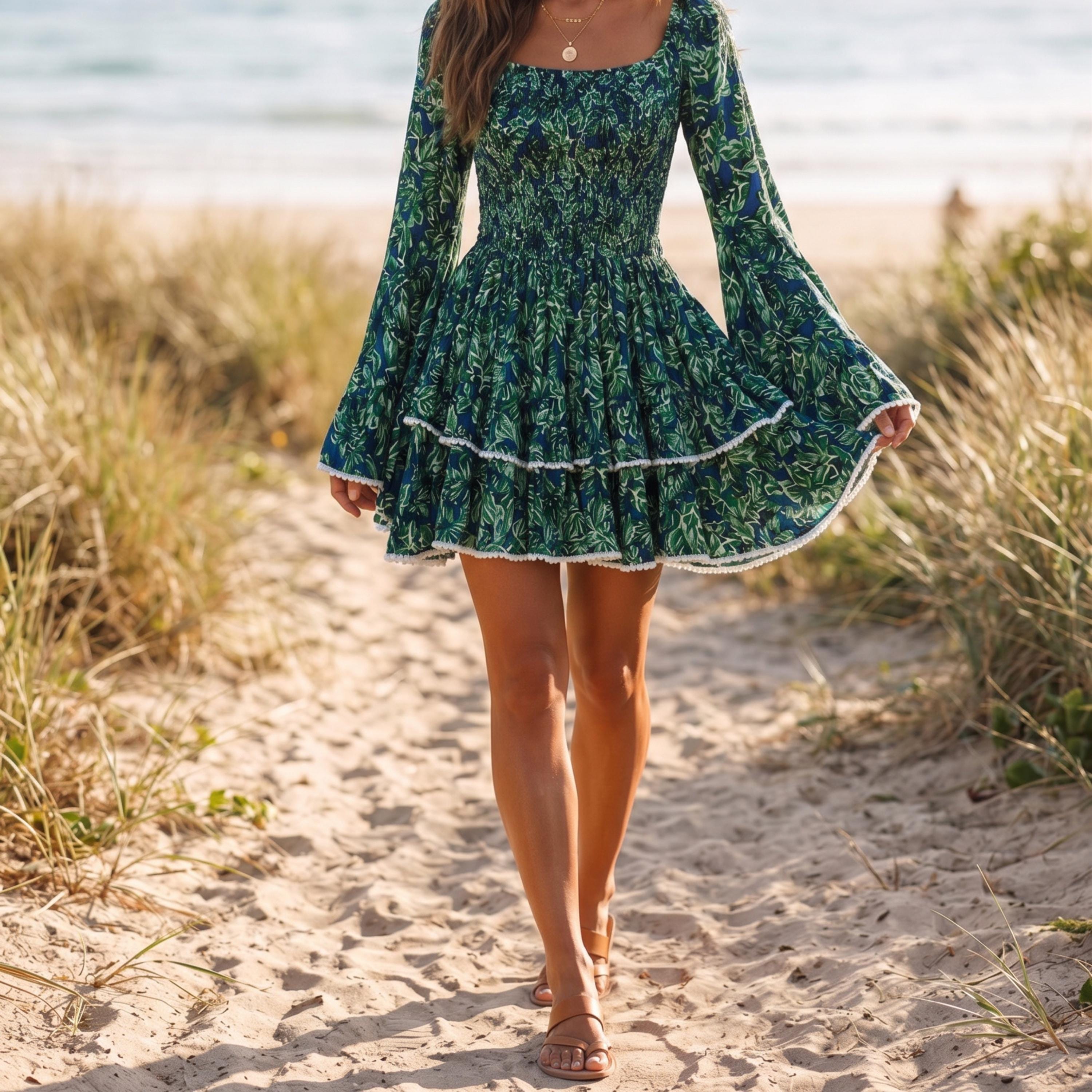 A woman wearing a green floral dress walks along a sandy beach.