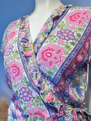 A mannequin wearing a colorful, patterned dress with a wrap-style neckline and ruffled details.