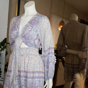 A mannequin wearing a purple and white patterned dress with a tie waist, displayed in a clothing store.