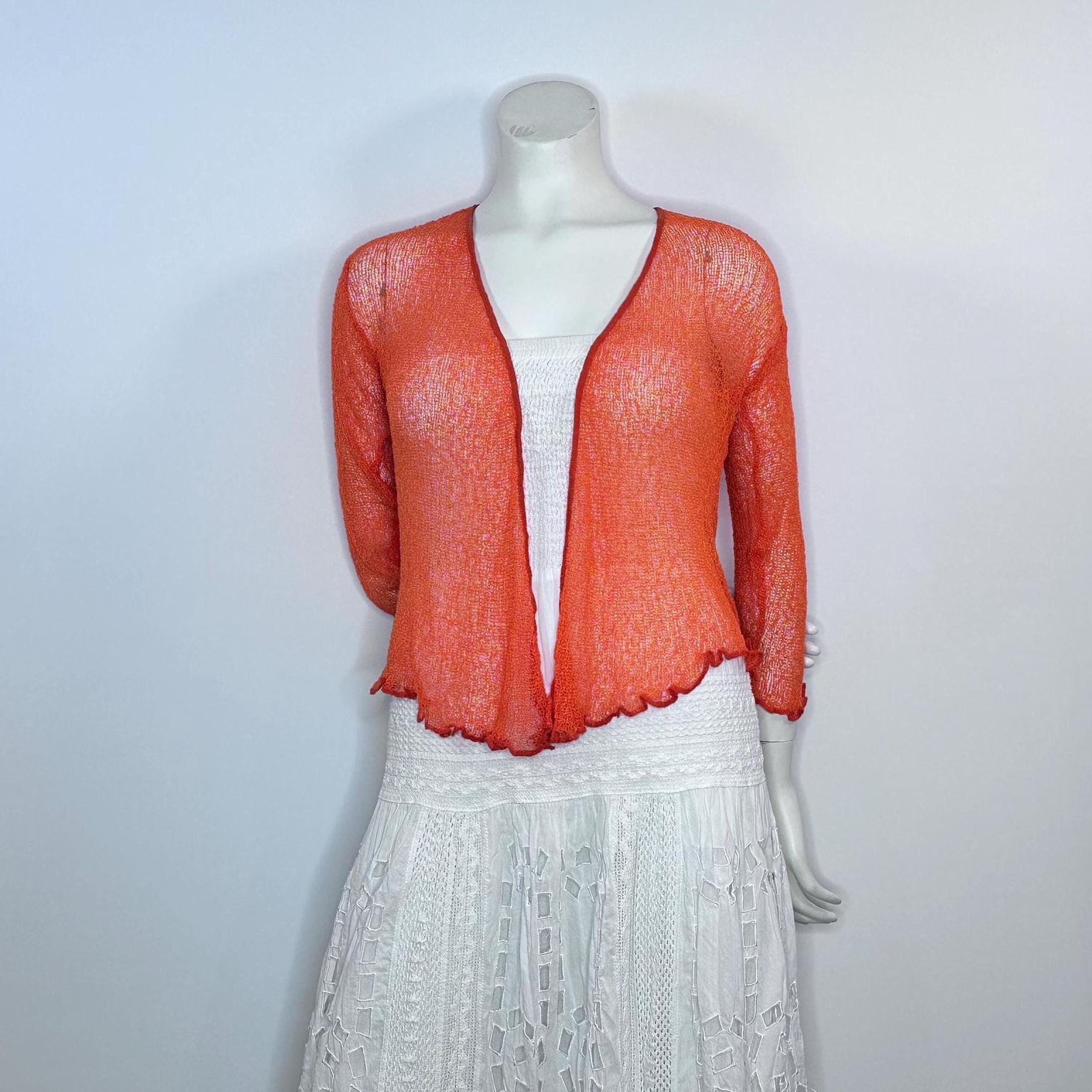 A mannequin wearing a red lace top and a white lace skirt, with the top featuring a sheer, lace-like design.
