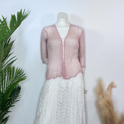 A mannequin wearing a pink lace top and a white lace skirt, displayed against a white background with a green plant to the left.
