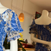 two mannequins wearing colorful floral dresses, with one dress being blue and the other being a mix of blue and white floral patterns.