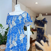 A mannequin wearing a blue floral dress with a high neckline and puffed sleeves, displayed in a clothing store.