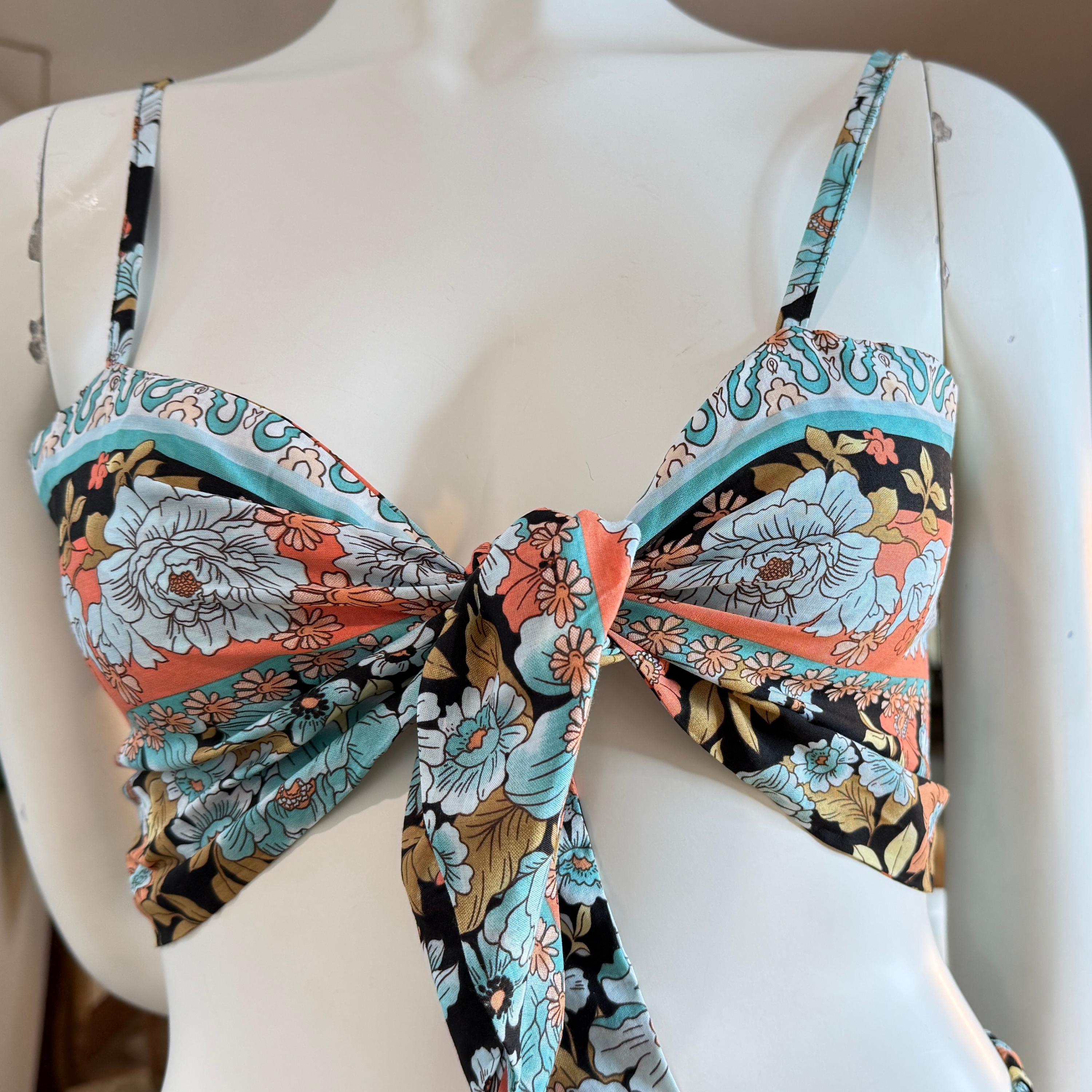 A mannequin wearing a colorful floral print bikini top with a tie at the front.