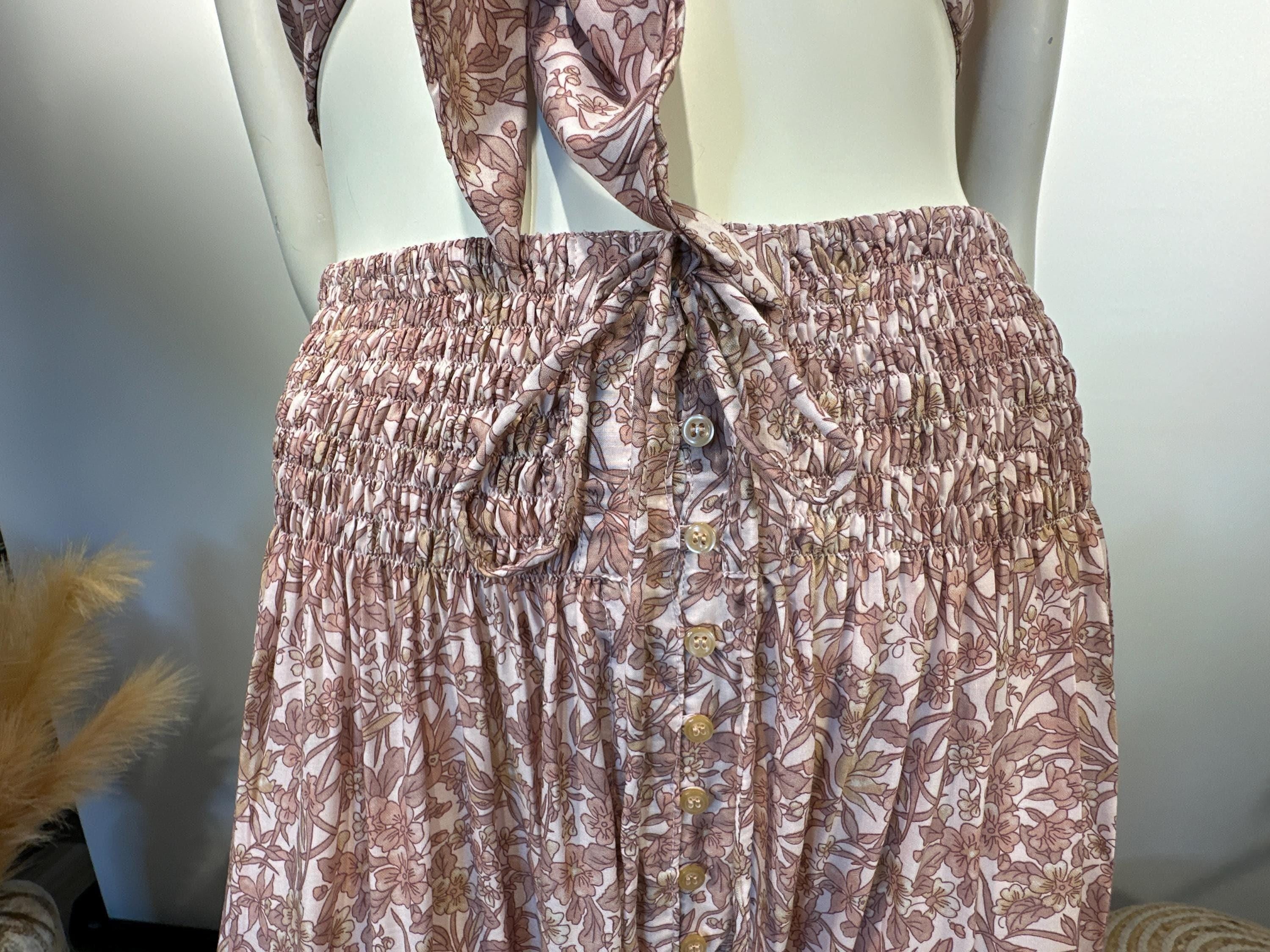 A mannequin wearing a pink and white floral print skirt with a ruffled waistband and buttons.