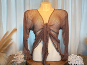 A mannequin wearing a brown knitted top with a tie front, displayed on a wooden stand with coral and other decorative items.