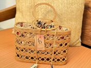 A woven straw handbag with a handle and a tag displaying the letters 'CD' is placed on a wooden surface.