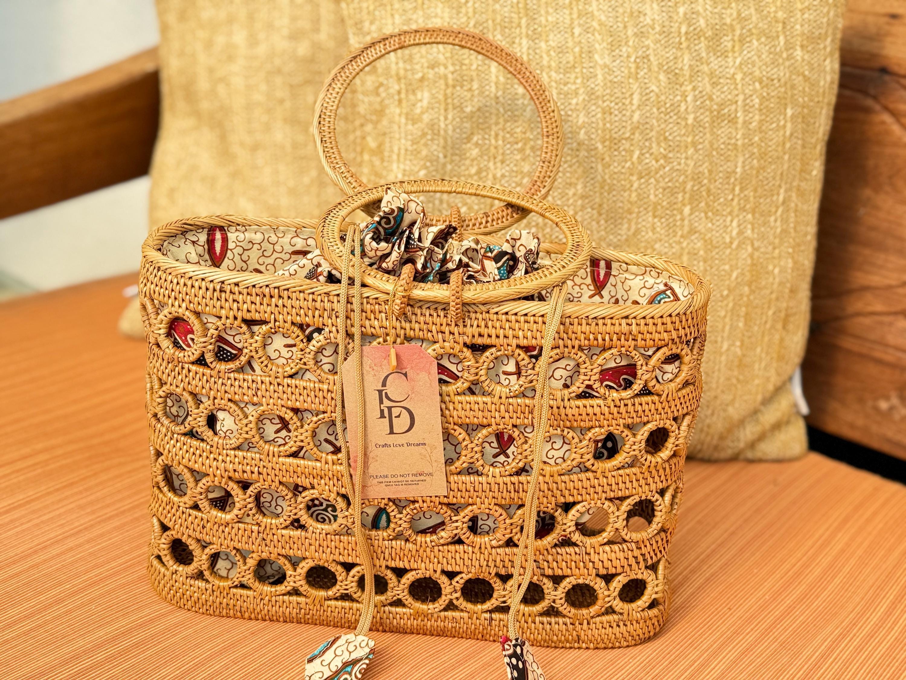 A woven straw handbag with a handle and a tag displaying the letters 'CD' is placed on a wooden surface.