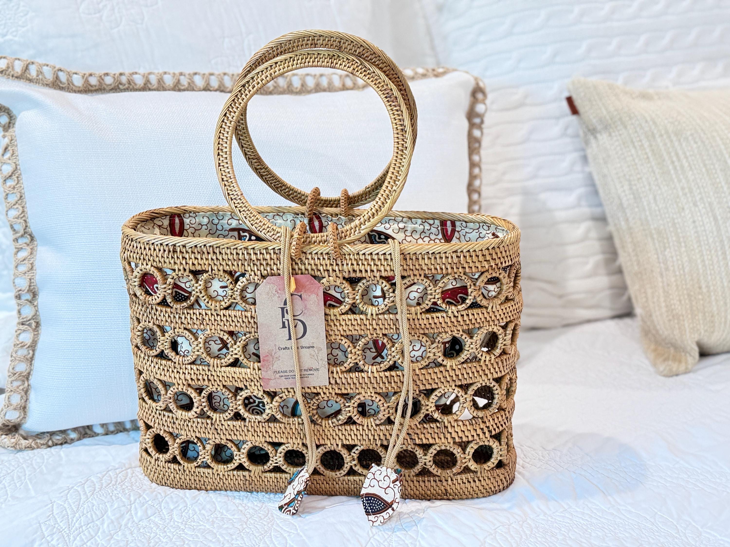A woven handbag with a round handle and a tag attached, placed on a white bedspread.