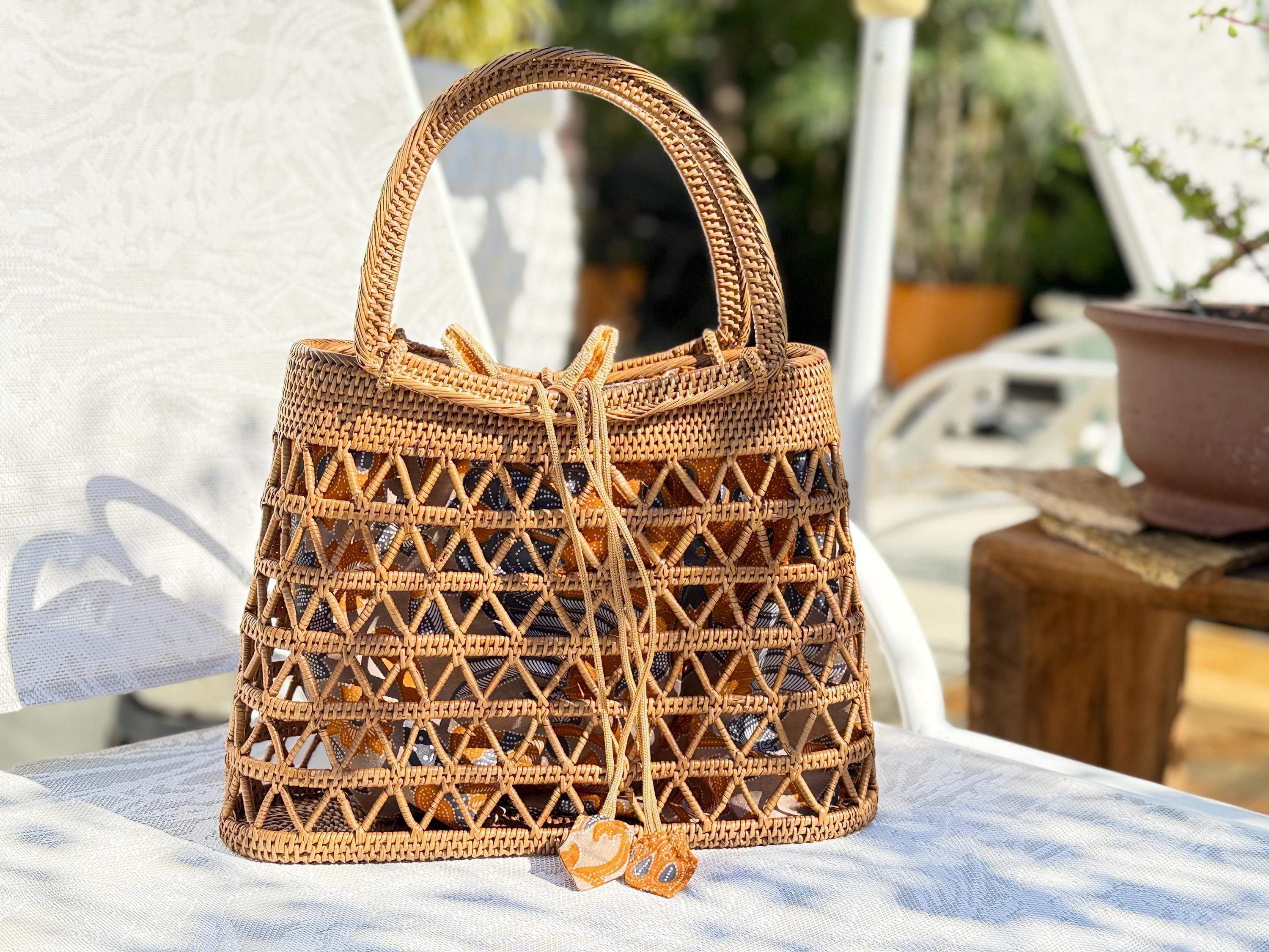 A woven straw handbag with a distinctive pattern sits on a white chair, with a potted plant visible in the background.
