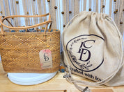 a woven straw bag and a wooden bag with a drawstring closure, both placed on a wooden surface.