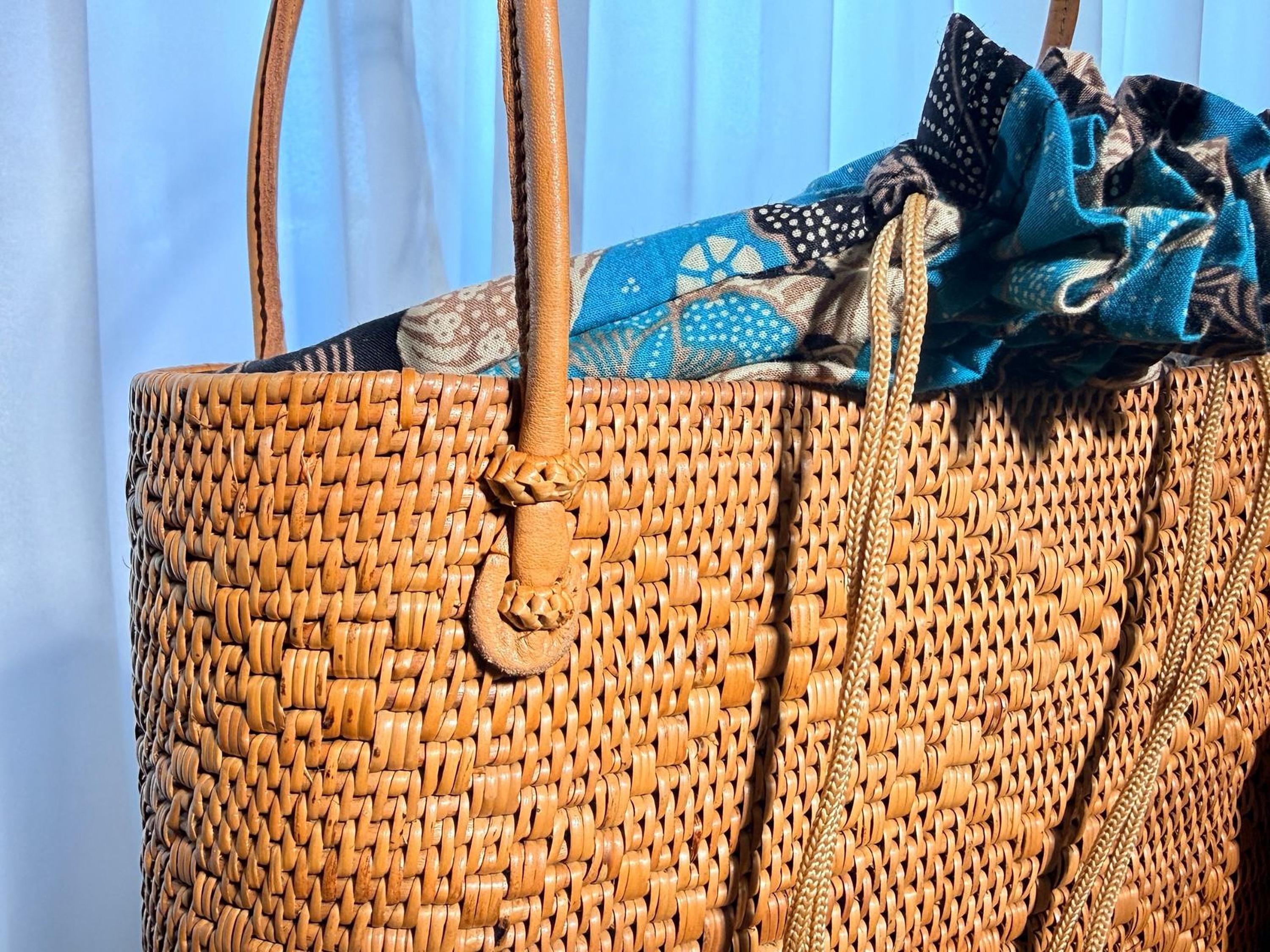 A woven straw bag with a patterned fabric draped over it, placed against a blue background.