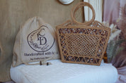 a handcrafted woven bag and a woven purse placed on a white cushion.