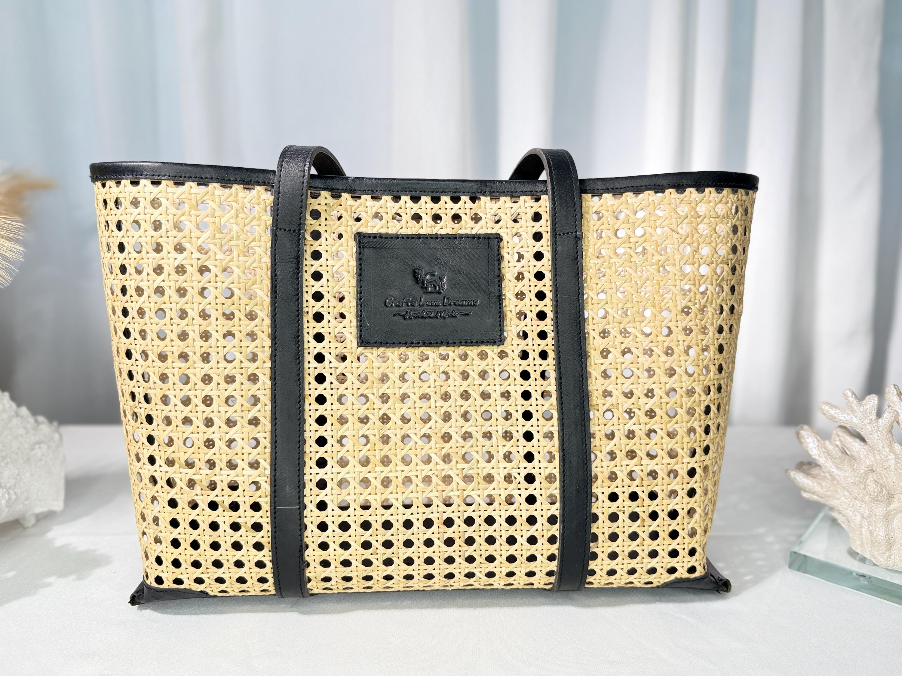 A woven tote bag with a black leather label, placed on a white surface against a blue background.