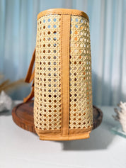 A woven basket with a tan-colored interior and a brown handle, placed on a wooden surface against a blue background.