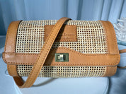 A brown woven purse with a metal clasp and leather trim, featuring a textured pattern.