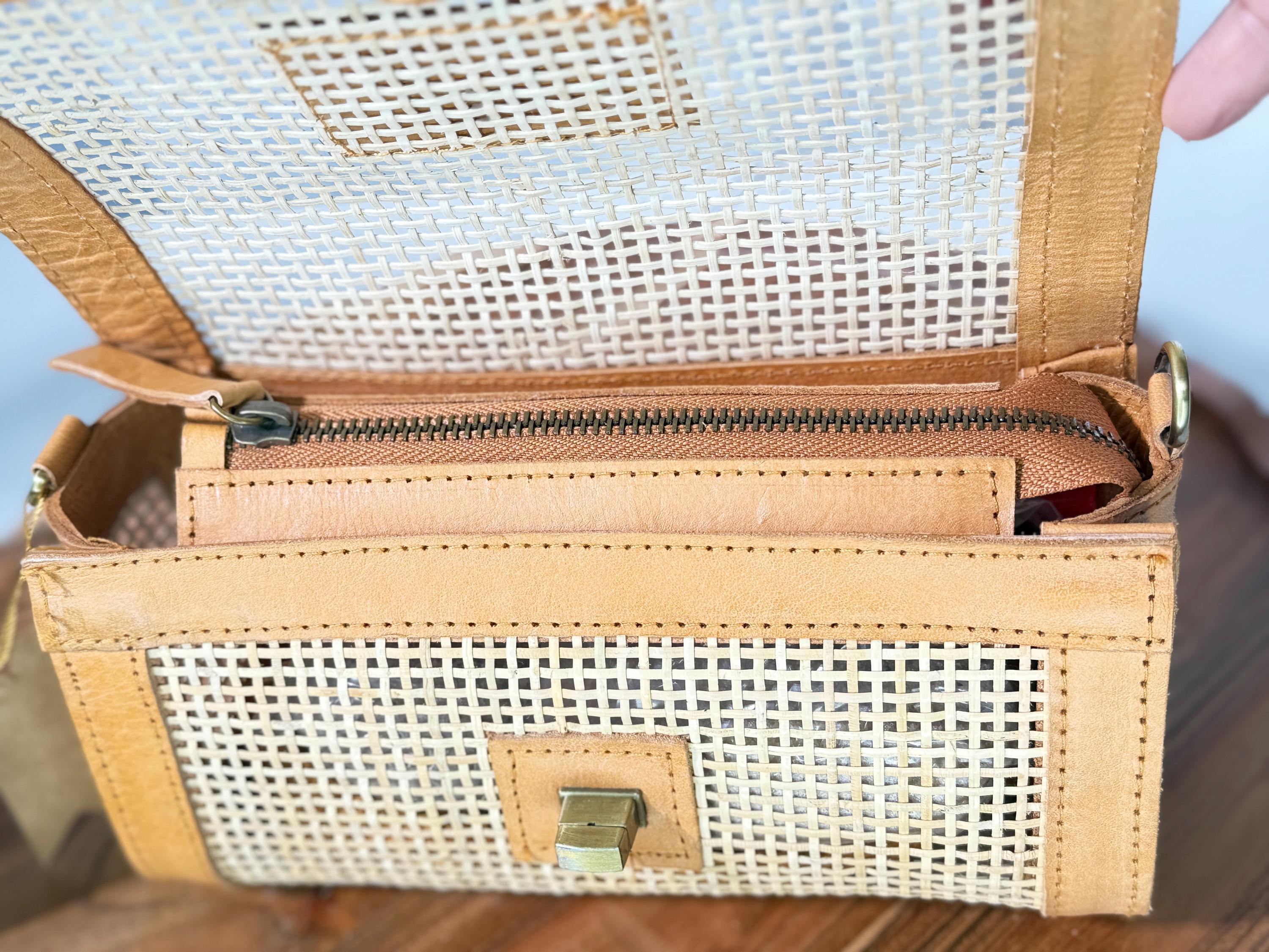 a tan-colored handbag with a woven texture, featuring a zipper closure and a small metal clasp.