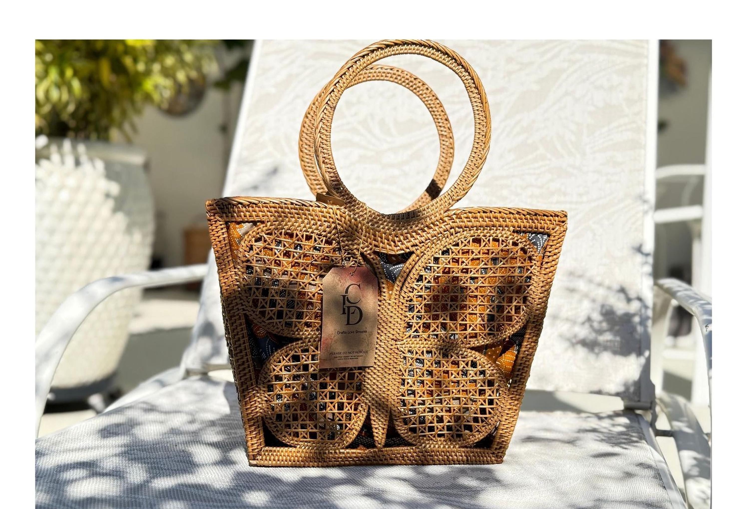 A woven handbag with a butterfly pattern sits on a white chair, with a tag attached to it.
