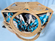 A woven basket with a handle, featuring a patterned fabric inside.