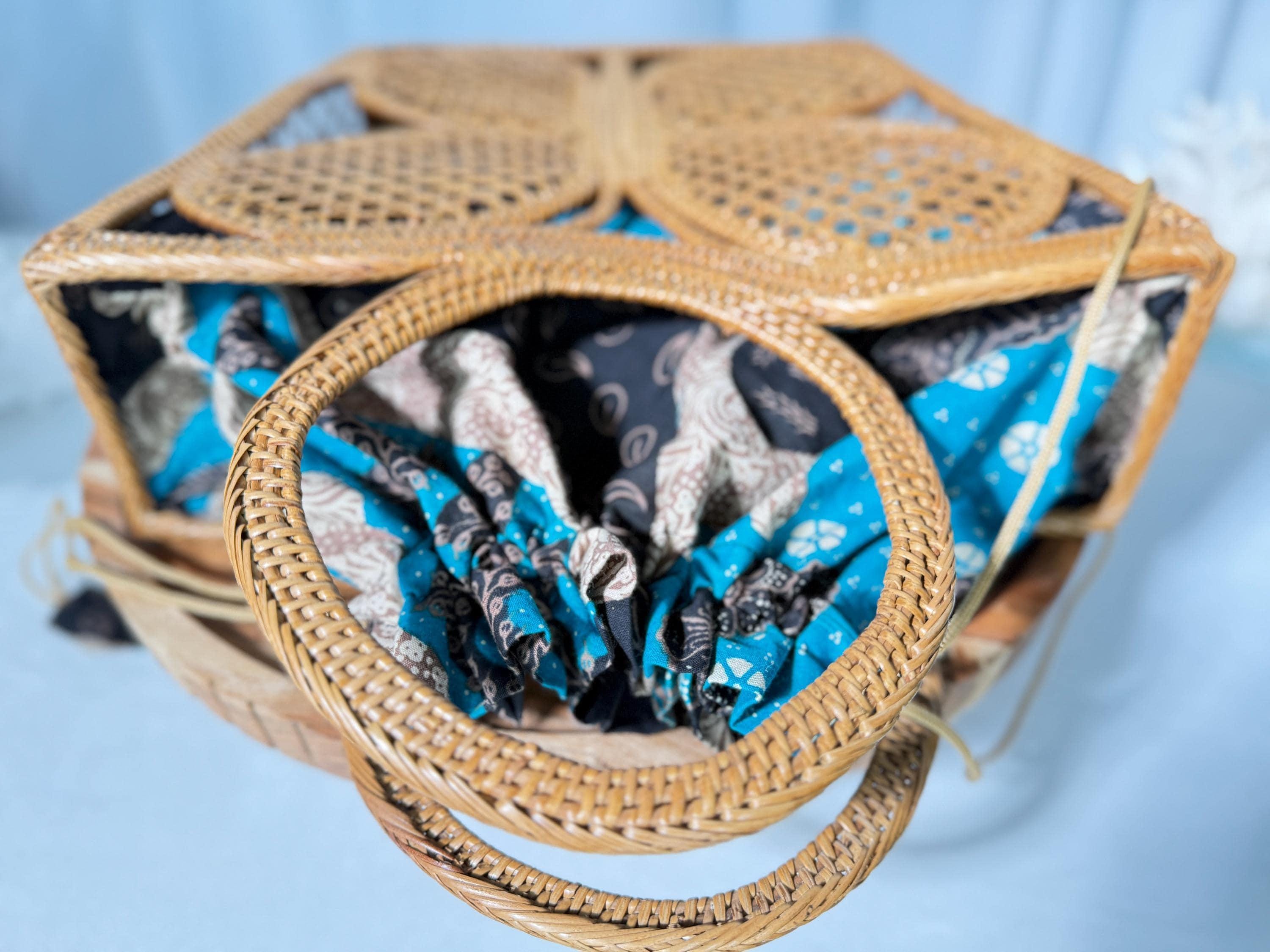 A woven basket with a handle, featuring a patterned fabric inside.
