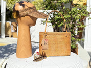 a wooden headband, a woven straw handbag, and a pair of sunglasses on a white table.