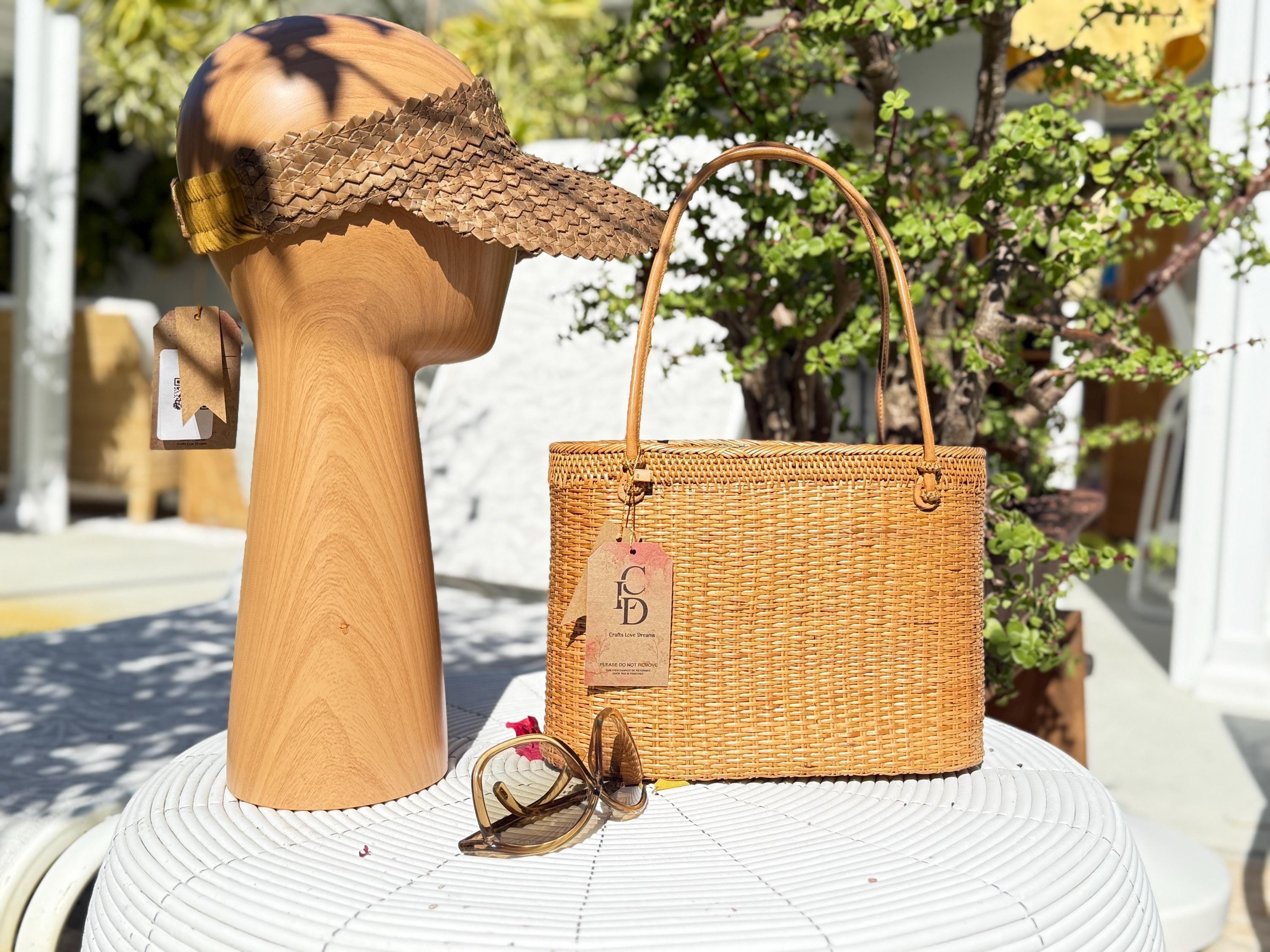 a wooden headband, a woven straw handbag, and a pair of sunglasses on a white table.