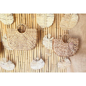 two woven bags hanging on a bamboo wall.