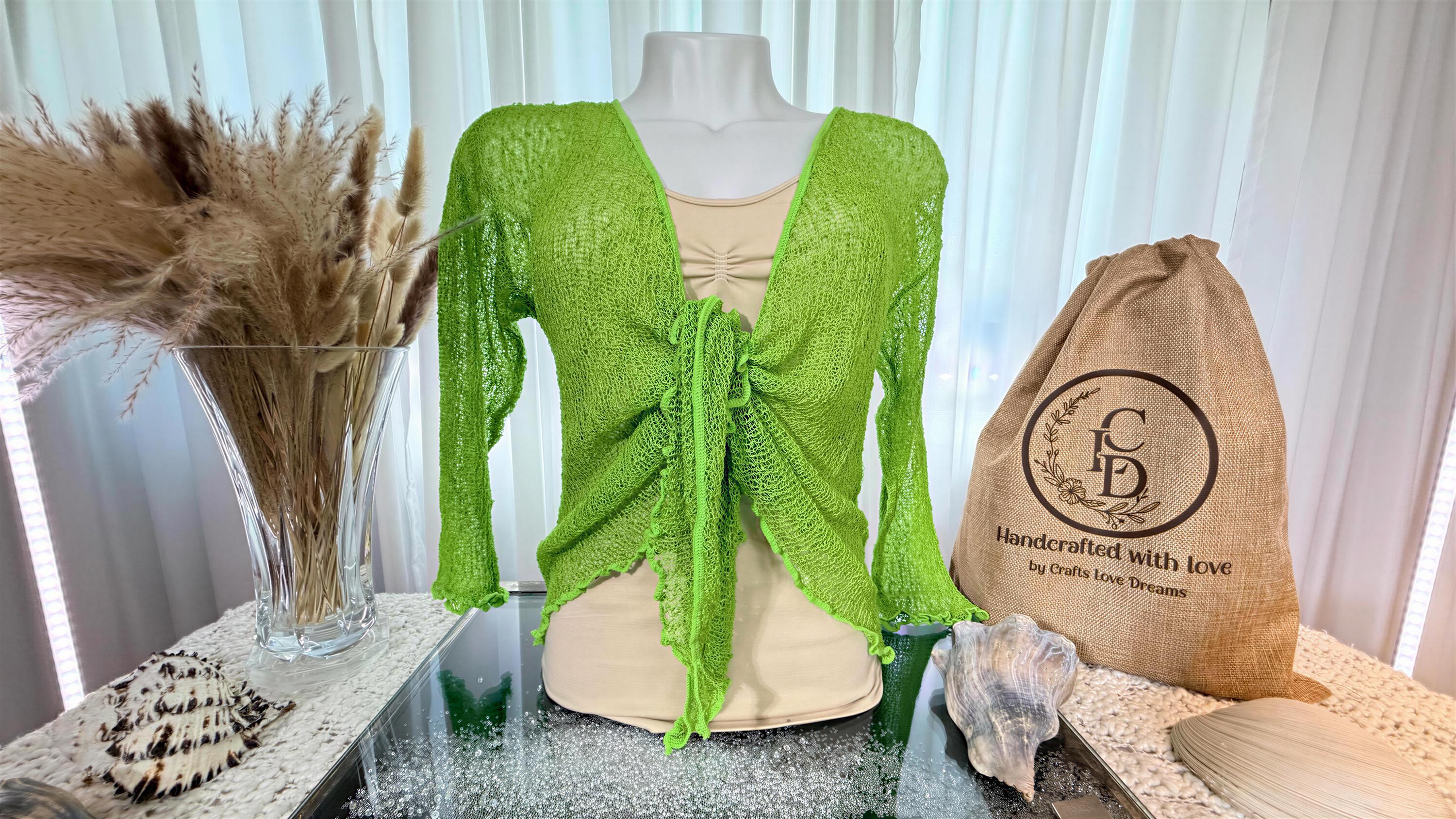 Bright green sheer knit tie-front cardigan shrug on a mannequin beside a Crafts Love Dreams jute dust bag and dried pampas grass
