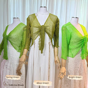 Three mannequins wearing the sheer knit cardigan shrug in Spring Green, Moss Green and Bright Green over white lace dresses